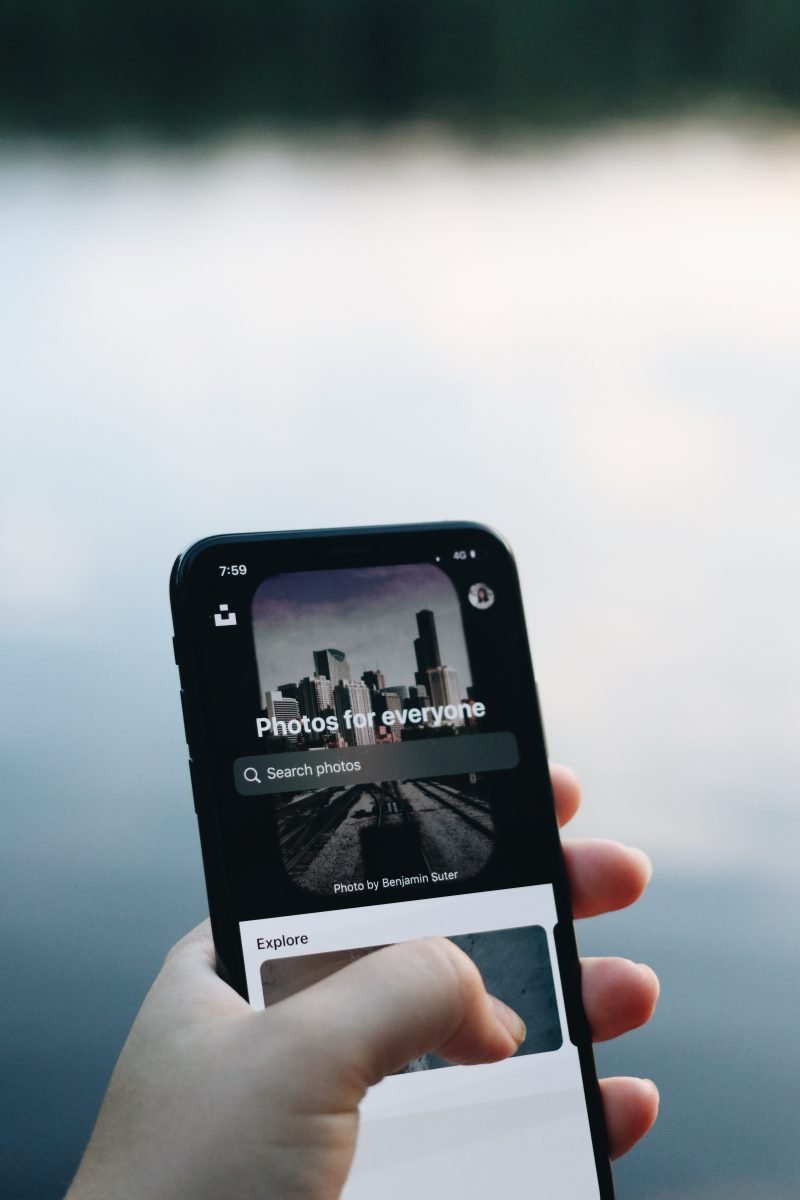 Person holding their cell phone in front of a lake